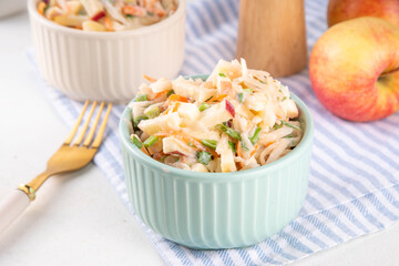 Asian Apple Slaw Salad with Apples, cabbage, carrot and spring onions. Healthy fall vegetable salad with yogurt dressing, in portioned bowls on kitchen table 