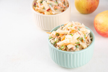 Asian Apple Slaw Salad with Apples, cabbage, carrot and spring onions. Healthy fall vegetable salad with yogurt dressing, in portioned bowls on kitchen table 