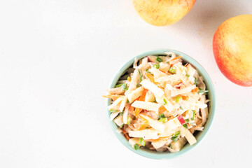 Asian Apple Slaw Salad with Apples, cabbage, carrot and spring onions. Healthy fall vegetable salad with yogurt dressing, in portioned bowls on kitchen table 
