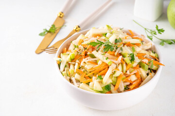 Homemade seasonal  Apple Slaw Salad with Apples, cabbage, carrot and spring onions. Healthy fall vegetable salad with yogurt dressing, in portioned bowls on kitchen table 
