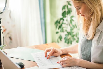 woman carefully examines a document, focusing intently on her work. The natural light and greenery...