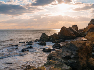 Beautiful seascape at sunset in Black sea coast with rocks and sunbeams lighting through clouds.