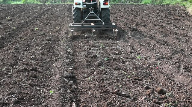 Farmer plowing stubble field in tractor preparing plows the land, agricultural works at farmland