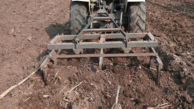 Farmer plowing stubble field in tractor preparing plows the land, agricultural works at farmland