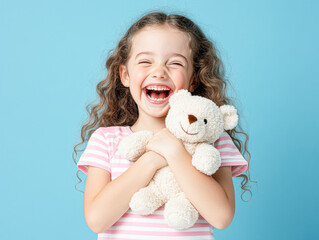 A young girl is holding a teddy bear and smiling