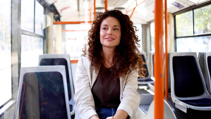 Beautiful, mid adult woman riding in a city bus and enjoying