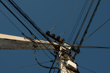 Bottom view of a electric pole with wires against blue sky	