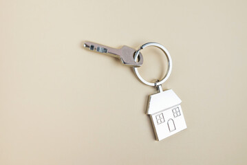 metal keychain house and keys on a beige background with copy space.