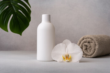 White bottle with orchid flower and rolled towel, symbolizing spa and skincare