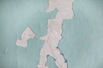 Cracked, peeling paint on the wall. A wall with old cracked blue paint. Patterns of cracks.