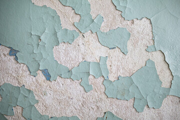 Cracked, peeling paint on the wall. A wall with old cracked blue paint. Patterns of cracks.