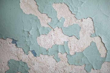 Cracked, peeling paint on the wall. A wall with old cracked blue paint. Patterns of cracks.