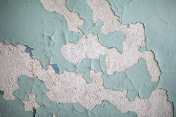 Cracked, peeling paint on the wall. A wall with old cracked blue paint. Patterns of cracks.
