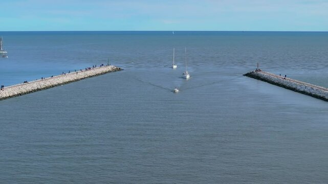 aerial view of sailing yachts coming into the breakwater inlet Livenza, in Caorle, Italy