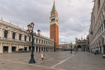 Naklejka premium A girl in a hat running with the pigeons in St. Mark's square in Venice
