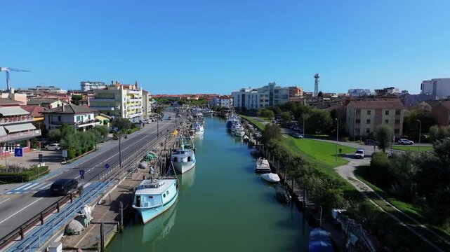 low-flying aerial of the commercial canal in Caorle, Italy, slowly rising to reveal the Adriatic Sea