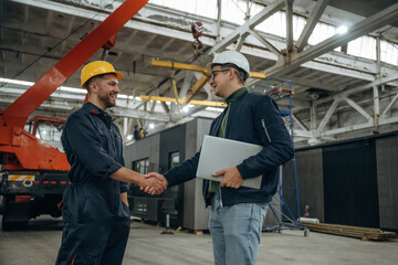 Friendly handshake. Two male factory workers are in the warehouse © standret