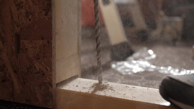 A close-up shot of a drill bit piercing through wood, showcasing the precision and detail involved in woodworking.