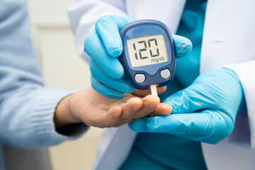 Asian doctor using digital glucose meter for check sample blood sugar level to treatment diabetes.