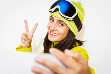 Young woman taking selfie picture with smart cell phone hiking mountain on snowy slope - Happy skier having fun in ski resort vacation - Winter lifestyle, extreme sport and happy people concept