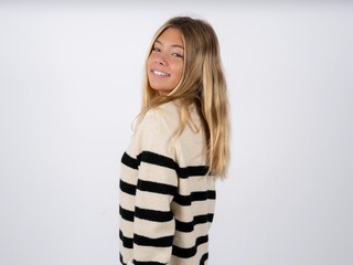 Satisfied pretty caucasian teen girl wearing striped knitted sweater over white beaming smile look camera