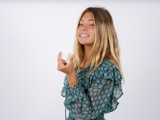 caucasian teen girl wearing green dress over white holding an invisible aligner ready to use it....