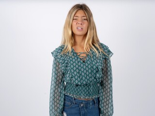 Portrait of dissatisfied caucasian teen girl wearing green dress over white smirks face, purses...