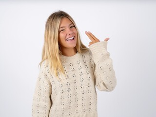 caucasian teen girl wearing knitted sweater over white foolishness around shoots in temple with fingers makes suicide gesture. Funny model makes finger gun pistol
