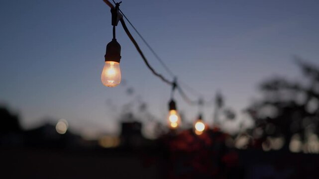 A closeup view of glowing string lights beautifully illuminating the twilight sky, evoking both warmth and tranquility
