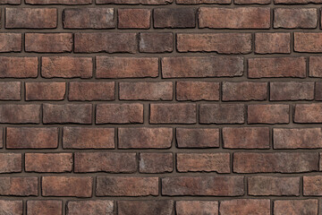 Obraz premium A dark red brick wall with a uniform arrangement of bricks creating a solid and classic texture with a deep rustic aesthetic 