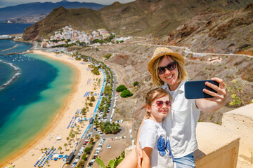 Happy moments captured by a mother and daughter at Las Teresitas Beach in Tenerife, with the coastline and mountains as their backdrop