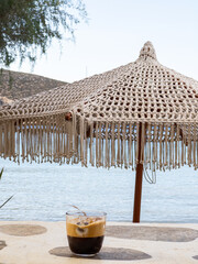 Greek Freddo Espresso under a woven umbrella on Vathi Beach, Sifnos Island 