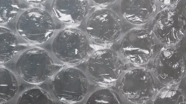Macro shot of bubble wrap under light, highlighting its inflated air cells and clear plastic structure, perfect for cushioning and protecting fragile items with a soft, flexible design.