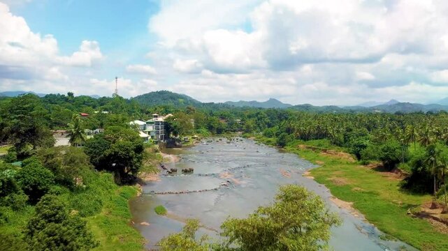 Elephants from the Pinnawala Elephant Orphanage gather on the rocky bank of the Maha Oya River in central Sri Lanka. Far flight. 4k 60 fps