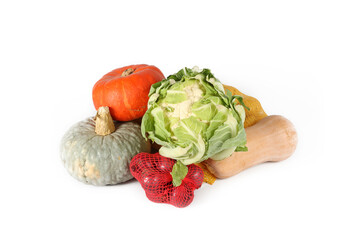 Group of autumn vegetables on a white background: cauliflower, butternut squash, net bag of potatoes, net bag of onions, and a green pumpkin
