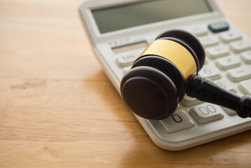 Gavel hammer judge and white calculator on wooden table background. Tax law, financial law or...