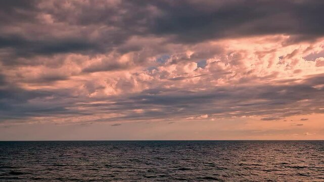 Beautiful Sunset Of A Colorful Rainy Sky Of Puffy Clouds and Sun over a Calm Sea. Amazing Colored Seascape of a Incredible Nlue Orange Coral Sunset Sky Clouds and Calm Ocean. Sea Sky Background Planet