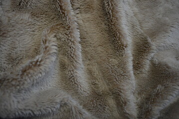 Fabrics, soft materials, bedspread, blanket made of synthetic materials. Gray-brown, fluffy and soft background in the form of long fur.