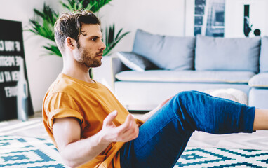 Obraz premium Young man training asana at home looking determined