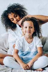 Woman brushing hair of child on sofa