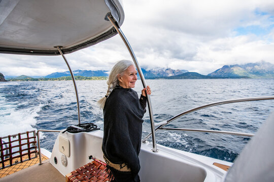 Smiling woman with long white hair standing on yacht on Lake Nahuel Huapi