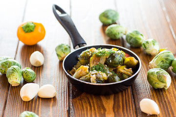 Brussel sprouts cooked with vegetables and spices, on a wooden table