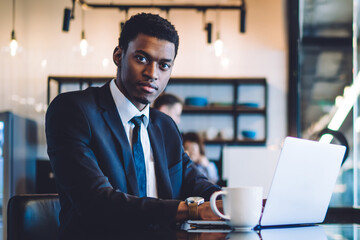 Black man in formal wear working near window