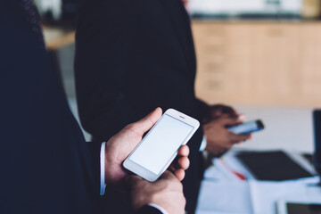 Multiracial coworkers with smartphones standing in meeting room