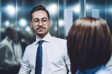 Successful colleagues talking and discussing business information in elevator