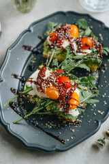 Avocado sandwich with mozzarella, dried and fresh tomatoes, and arugula