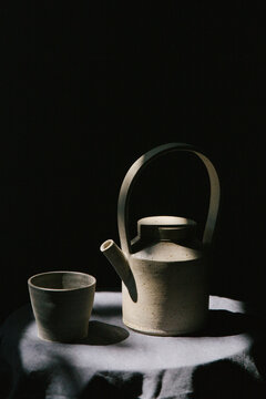 A ceramic tea set catching light in a moody setting.