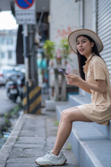 Fototapeta premium A woman in a yellow dress is sitting on a step with her phone in her hand