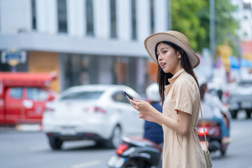 She is looking at the phone while a car is driving by