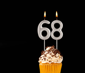 Birthday cupcake on black background - Number 68 shaped candles.